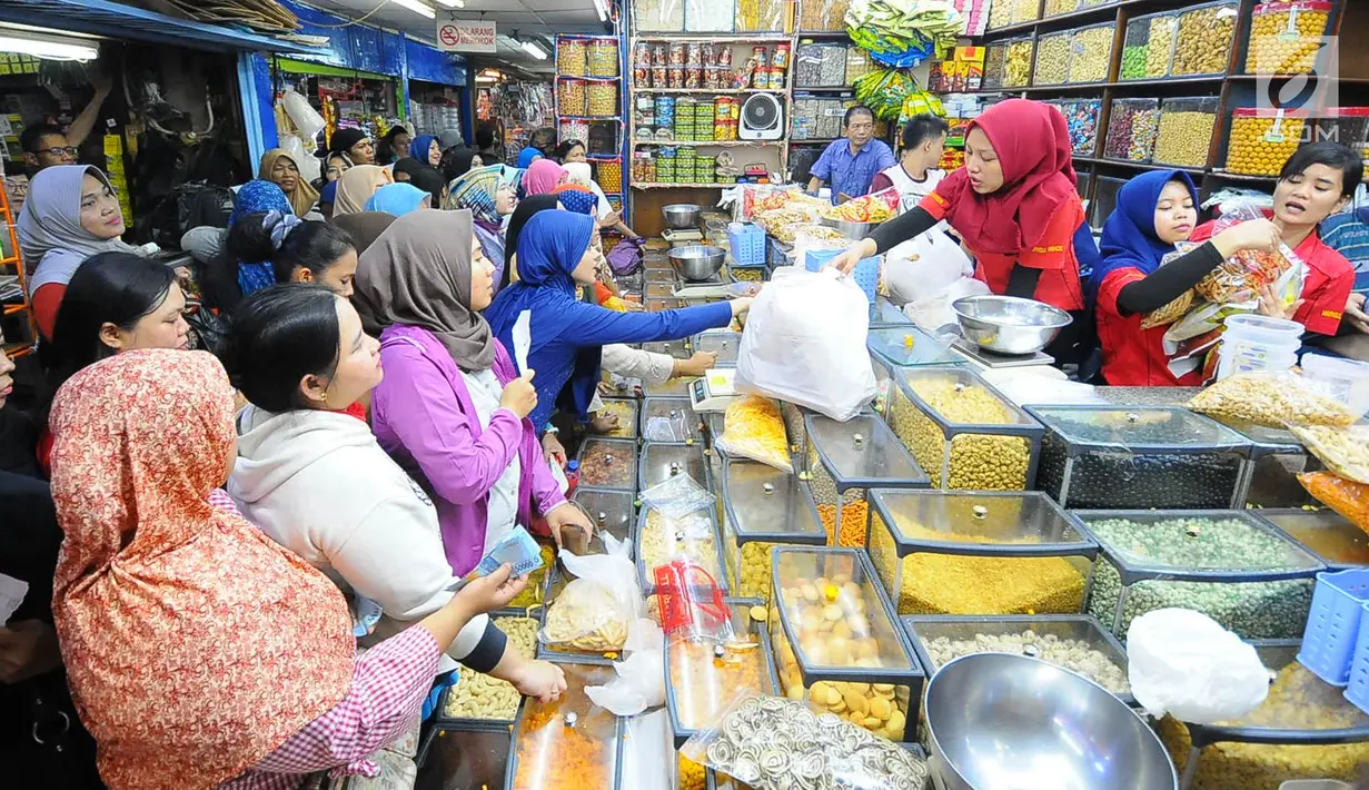 Pedagang kue kering melayani pembeli di Pasar Jatinegara, Jakarta, Senin (27/5/2019). Jelang Idul Fitri 2019, banyak warga berburu makanan ringan seperti kue kering untuk jamuan di hari raya. (Liputan6.com/Angga Yuniar)