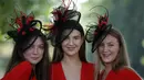 Tiga wanita memakai hiasan kepala berpose saat tiba untuk menyaksikan balap kuda Royal Ascot horse di Ascot, London, (20/6). Balap kuda ini telah diadakan di Berkshire sejak tahun 1711. (AFP Photo/Daniel Leal-Olivas)