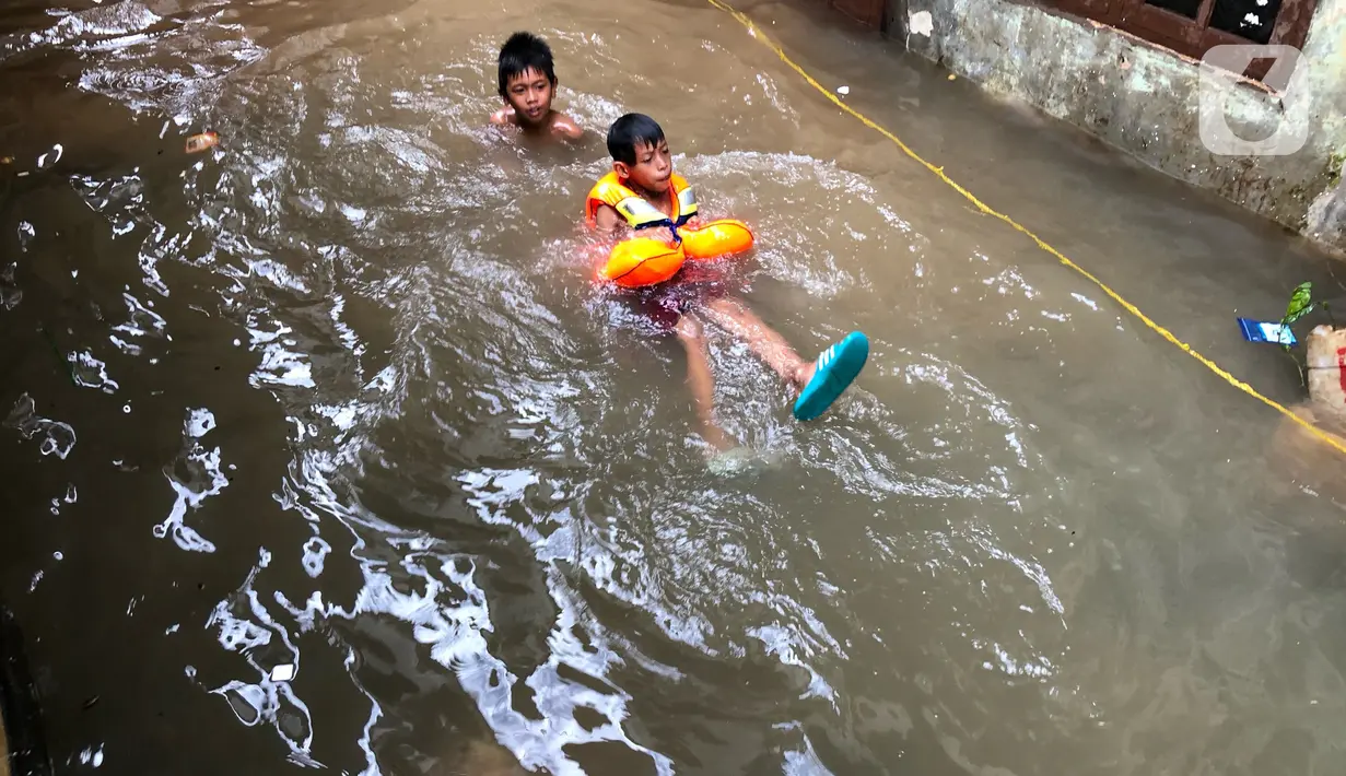 Anak-anak bermain di tengah banjir yang merendam kawasan Kebon Pala, Jakarta Timur, Selasa (25/2/2020). Akibat banjir yang tak kunjung surut, aktivitas warga di kawasan tersebut menjadi terganggu, terlebih dengan adanya pemadaman listrik. (Liputan6.com/Immanuel Antonius)