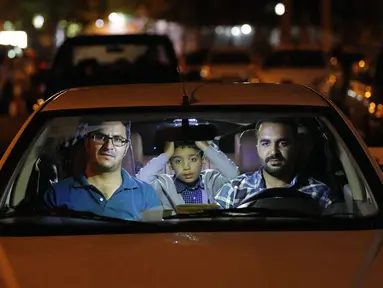Warga duduk dalam mobil saat upacara keagamaan pada bulan suci Ramadan di tengah pandemi COVID-19, Teheran, Iran, Kamis (30/4/2020). Keluarga-keluarga di Iran menghadiri upacara keagamaan drive-in karena tidak memiliki kesempatan untuk salat di masjid setelah berbuka puasa. (STR/AFP)