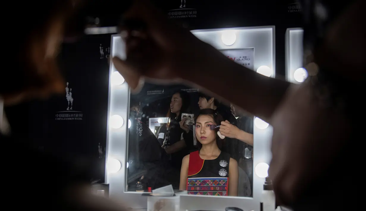 Seorang model saat dirias wajahnya di belakang panggung sebelum memamerkan koleksi oleh Zhang Kejia selama China Fashion Week di Beijing (26/3). (AFP Photo/Nicolas Asfouri)
