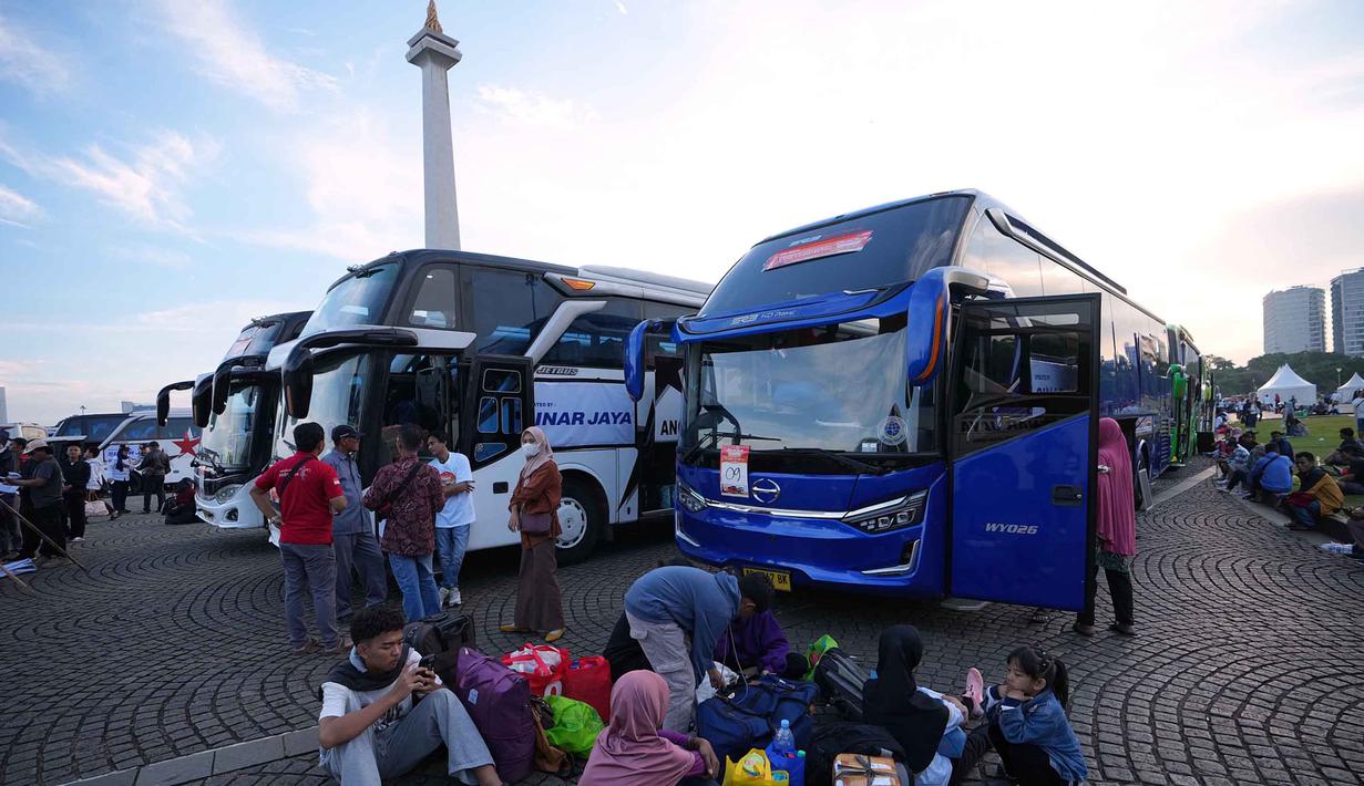 Sehari sebelumnya, Senin (16/3/2026), Pemprov DKI Jakarta telah melepas 388 unit sepeda motor milik pemudik dari Terminal Pulogadung menggunakan 15 truk agar dapat digunakan berlebaran di kampung halaman. Tampak dalam foto, orang-orang menunggu untuk menaiki bus yang akan mengangkut mereka ke kampung halaman untuk merayakan Hari Raya Idul Fitri 1447 Hijriah dalam perjalanan mudik gratis yang diselenggarakan oleh Pemerintah Provinsi Jakarta di Lapangan Monumen Nasional, Selasa 17 Maret 2026. (AP Photo/Achmad Ibrahim)