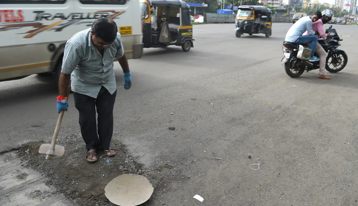 Dadarao Bilhore menutup jalan berlubang di jalan raya kota Mumbai, 29 Agustus 2018. Dadarao melakukan hal itu setelah putranya yang berusia 16 tahun meninggal dunia pada 2015 akibat kecelakaan lalu lintas karena jalanan berlubang. (INDRANIL MUKHERJEE/AFP)