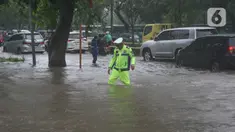 Polisi mengecek ketinggian genangan banjir yang menutupi Jalan Letjen Suprapto, Cempaka Putih, Jakarta Pusat, Kamis (29/2/2024). (merdeka.com/Arie Basuki)