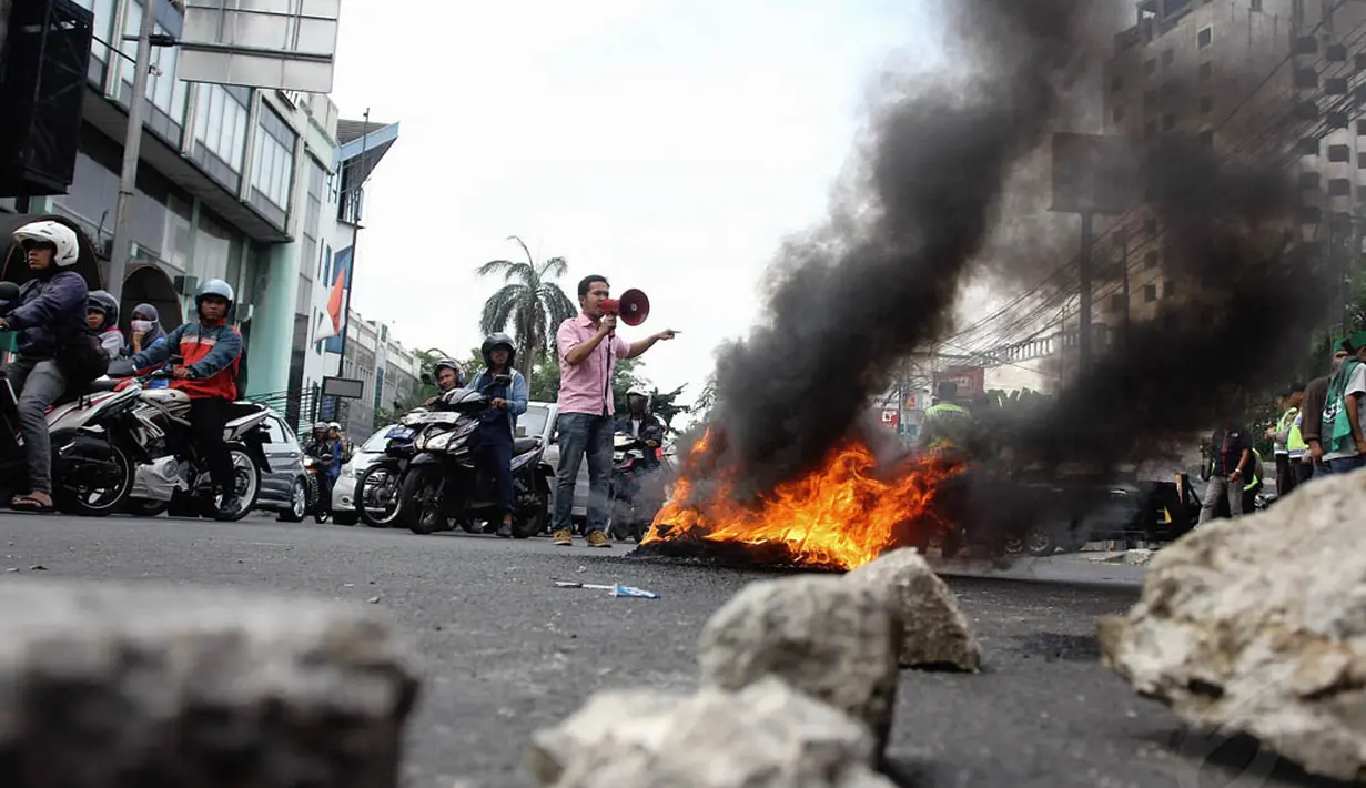 Massa menggelar orasi sambil membakar ban dan memblokade jalan raya Cikini, Jakarta, Selasa (18/11/2014). (Liputan6.com/Faizal Fanani)