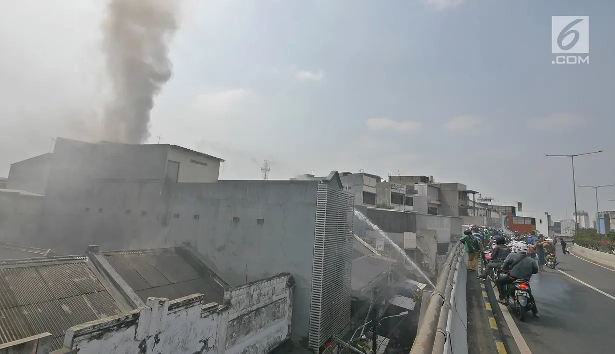 Sejumlah warga menyaksikan petugas pemadam kebakaran memadamkan api yang membakar gudang petasan di jalan Asemka, Jakarta, Jumat (21/6/2019). Sebanyak 27 unit mobil dinas pemadam kebakaran dikerahkan untuk memadamkan gudang penyimpanan petasan itu. (Liputan6.com/Herman Zakharia)