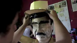 Pekerja memasangkan topi ke boneka raja narkoba Joaquin "El Chapo" Guzman saat menyelesaikannya di Reynosa, Meksiko (21/7/2015). Guzman melarikan diri dari penjara melalui terowongan yang ia buat pada bulan lalu. (REUTERS/Daniel Becerril)