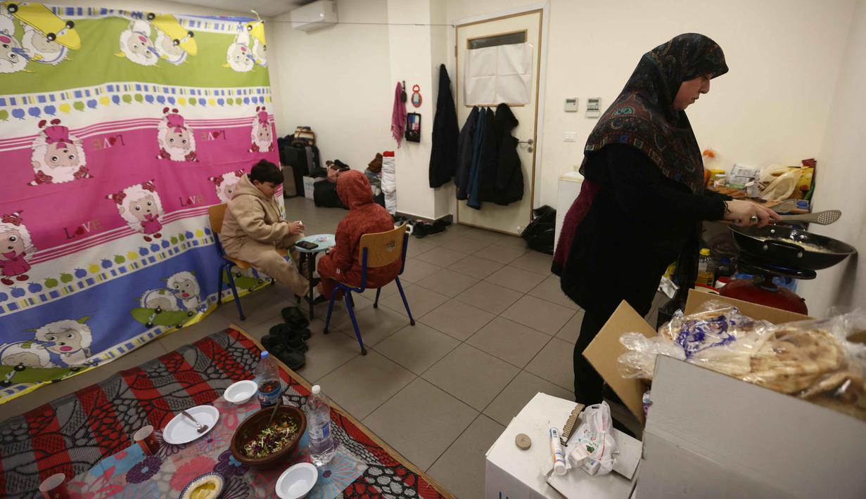 Menteri Urusan Sosial Lebanon, Haneen Sayed, mengatakan pada 7 Maret 2026, terdapat sekitar 517.000 orang telah terdaftar sebagai pengungsi di platform bantuan pemerintah. Tampak dalam foto, seorang perempuan pengungsi yang tinggal bersama keluarganya di ruang kelas sekolah, setelah melarikan diri dari serangan udara Israel di pinggiran selatan Beirut, Lebanon, duduk untuk berbuka puasa bersama, pada 7 Maret 2026. (Ibrahim AMRO/AFP)