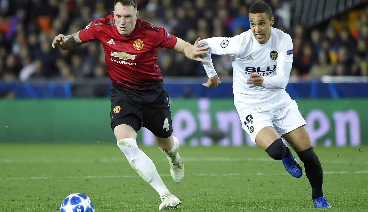 Bek Manchester United, Phil Jones melewati pemain Valencia, Rodrigo Moreno pada laga terakhir grup H Liga Champions yang berlangsung di stadion Mestalla, Valencia, Rabu (13/12). Manchester United kalah 1-2 atas Valencia. (AFP/Jose Jordan)