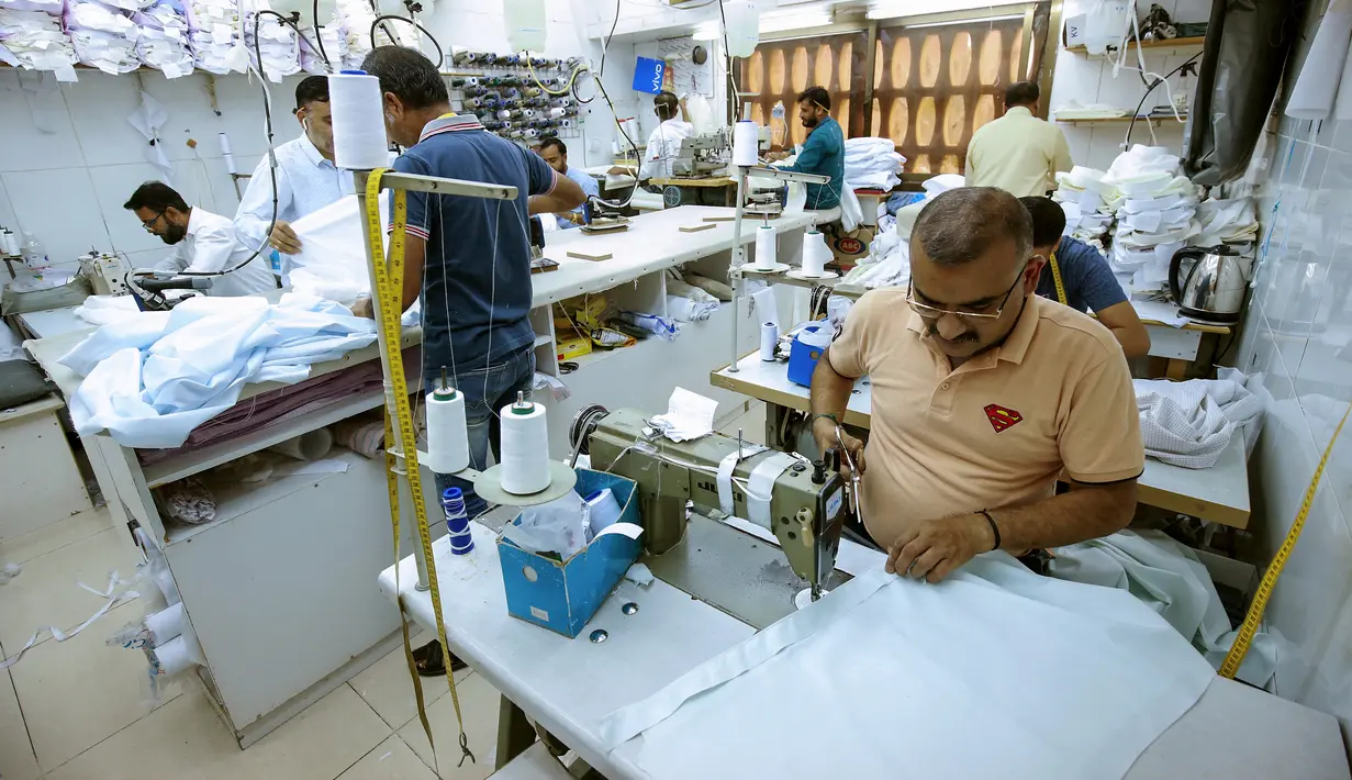 <p>Penjahit menyelesaikan produksi di tengah tingginya permintaan "dishdasha", pakaian tradisional Kuwait, di toko pakaian adat di Kuwait City pada 23 April 2022. Pakaian tradisional tersebut diburu pembeli, baik tua maupun muda, untuk Idul Fitri yang akan datang. (YASSER AL-ZAYYAT / AFP)</p>