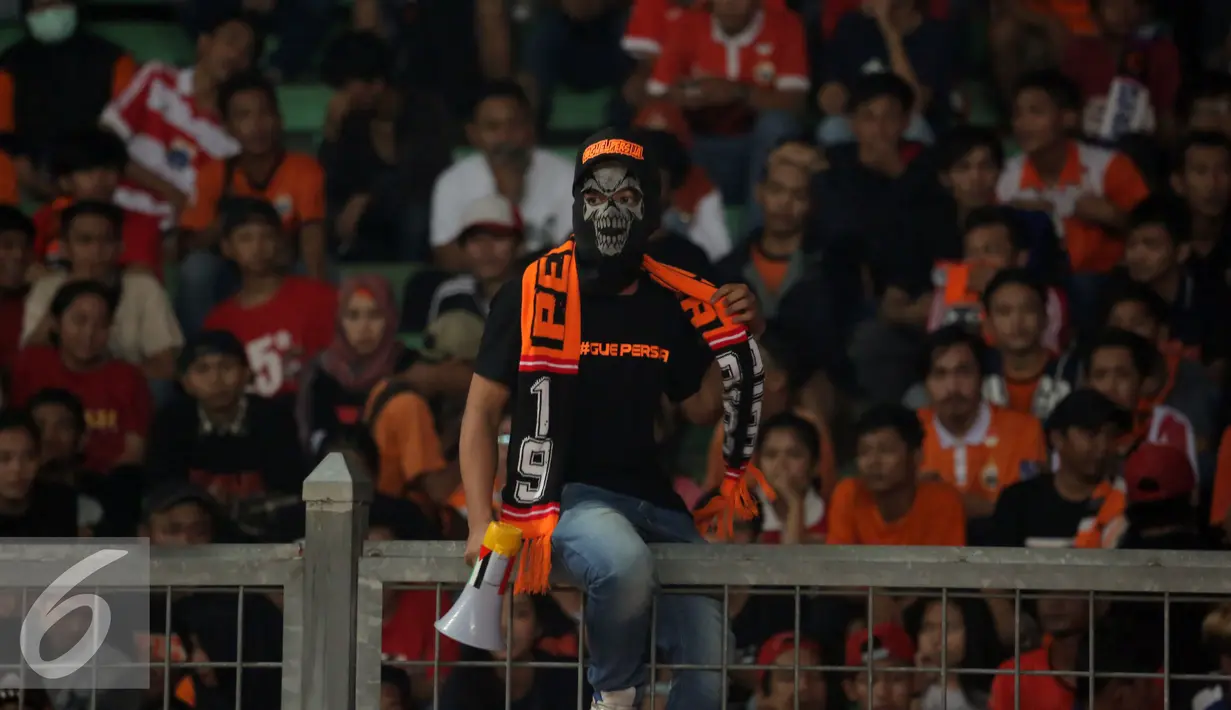 Suporter Persija menggunakan topeng saat menyaksikan laga Persija melawan PS TNI di Stadion GBK Jakarta, Jumat (10/6). Ribuan suporter Persija melakukan aksi meminta pengungkapan kasustewasnya M Fahreza (13/5) lalu. (Liputan6.com/Helmi Fithriansyah)