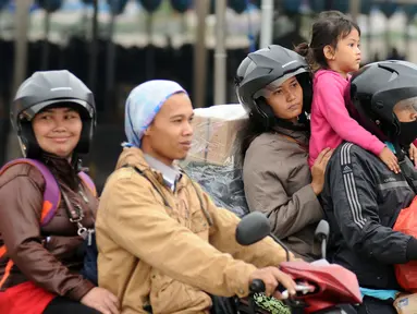 Pemudik membawa anaknya saat akan memasuki kapal penyereberangan di Dermaga 6 Pelabuhan Merak, Banten, Kamis (22/6). Meski sudah dihimbau oleh pihak berwenang, namun masih banyak pemudik bermotor yang membawa anak. (Liputan6.com/Helmi Fithriansyah)