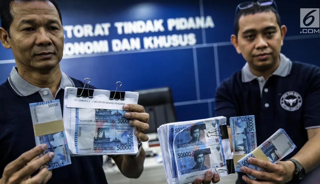 Petugas Direktorat Tindak Pidana Ekonomi Khusus Bareskrim Polri memperlihatkan uang palsu saat rilis di Bareskrim Polri, Jakarta, Jumat (16/6). Bareskrim Mabes Polri menangkap seorang pembuat uang palsu bernama Muhammad Amin. (Liputan6.com/Faizal Fanani)