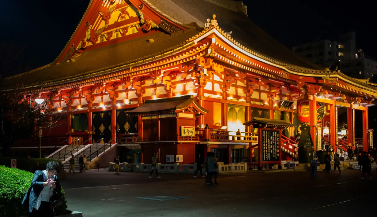 Seorang wanita melihat ponselnya di dekat kuil Asakusa di Tokyo (1/12). Pada abad kedua puluh, Asakusa adalah daerah hiburan utama di Tokyo. (AFP Photo/Martin Bureau)