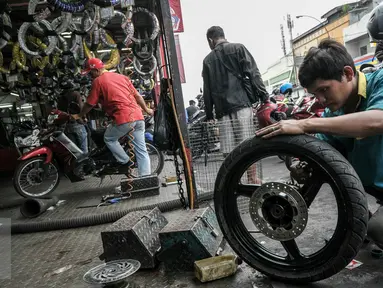 Montir sedang memperbaiki roda sepeda motor di bengkel kawasan Pasar Minggu, Jakarta, Kamis (30/6). Jelang Lebaran, pemudik motor mulai serbu jasa servis bengkel motor untuk persiapan mudik. (Liputan6.com/Yoppy Renato)