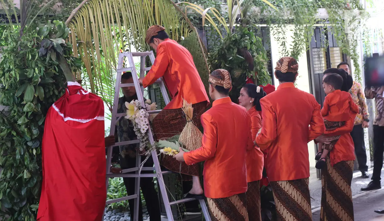 Presiden Joko Widodo (Jokowi) menaiki tangga untuk memasang bleketepe di kediamannya Jalan Kutai Utara, Solo, Selasa (7/11). Pemasangan bleketepe itu merupakan bagian dari prosesi adat pernikahan Kahiyang Ayu dan Bobby Nasution (Liputan6.com/Angga Yuniar)