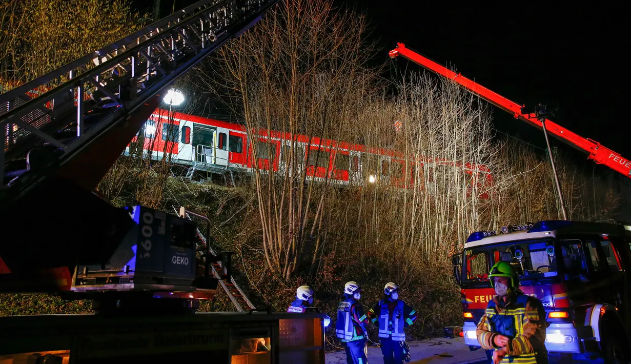 Petugas mengevakuasi rangkaian kereta komuter S-bahn yang tabrakan di Schaeftlarn di distrik Munich, Jerman pada 14 Februari 2022. Sekitar 95 orang berada dalam dua kereta yang mengalami kecelakaan itu dan seorang masinis terjebak di dalam kereta. (MICHAELA REHLE / AFP)