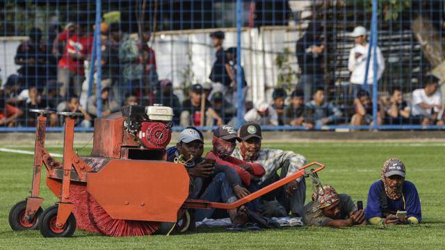 Para pekerja ikutan menonton latihan perdana Persija Jakarta di Lapangan Aldiron. (Bola.com/M. Iqbal Ichsan)