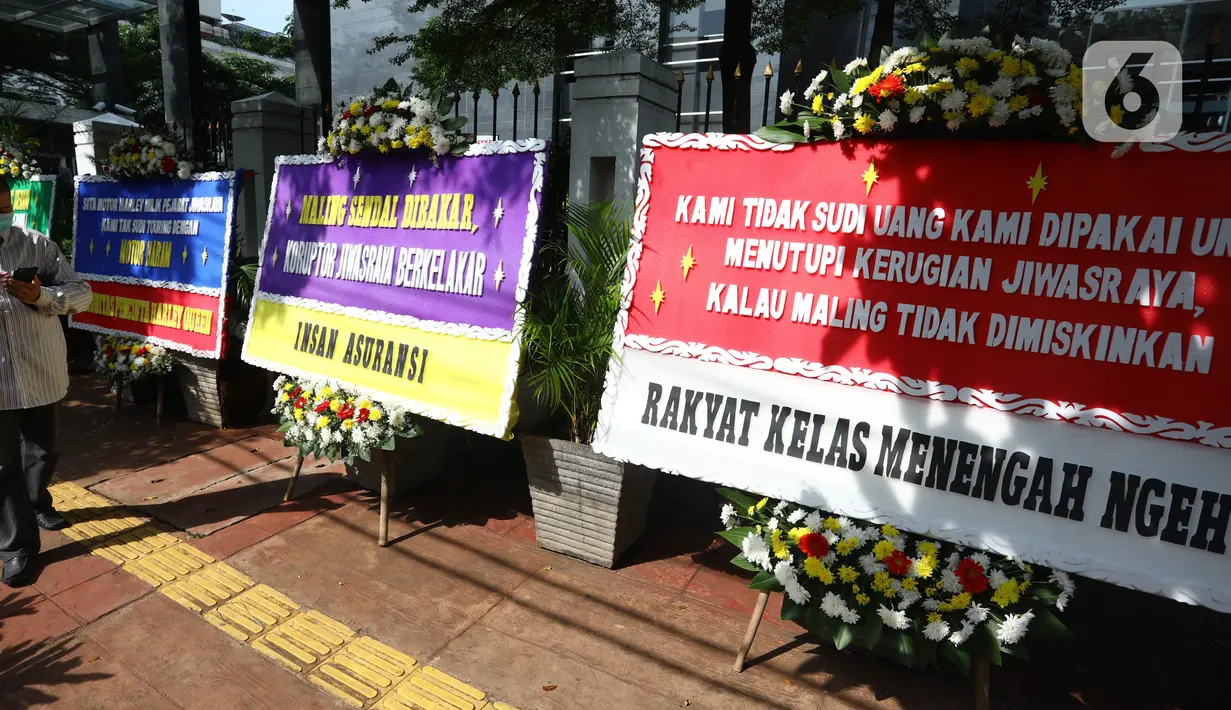 Pejalan kaki melintasi karangan bunga yang terpajang di depan Pengadilan Negeri Jakarta Pusat, Senin (12/10/2020). Karangan bunga yang mengharapkan keadilan tersebut berjejer menjelang sidang vonis terdakwa kasus dugaan korupsi di PT Asuransi Jiwasraya (Persero). (Liputan6.com/Angga Yuniar)