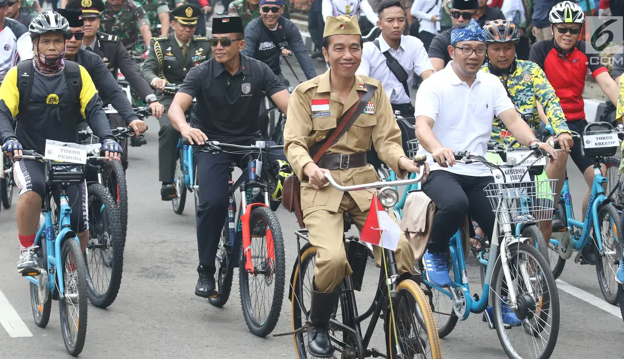 Presiden Joko Widodo atau Jokowi (tengah) didampingi Gubernur Jawa Barat Ridwan Kamil (kanan) saat mengikuti Bandung Lautan Sepeda, Sabtu (10/11). Kegiatan ini dalam rangka memperingati Hari Pahlawan. (Liputan6.com/Angga Yuniar)