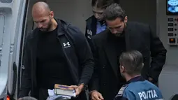 Andrew Tate (kiri) dan saudaranya Tristan (kanan) dibawa oleh polisi ke Pengadilan Banding di Bukares, Rumania, Selasa (10/1/2023). Tate, warga Inggris-AS berusia 36 tahun, ditahan otoritas Rumania atas dugaan perdagangan manusia, pemerkosaan, dan membentuk kelompok kejahatan. (AP Photo/Vadim Ghirda)