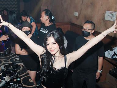 Putri Una terlihat ceria saat nge-DJ. Mengenakan pakaian serba hitam, ia mengangkat tangannya untuk mengajak pengunjung bergoyang. (Foto: Instagram/@putriuna)