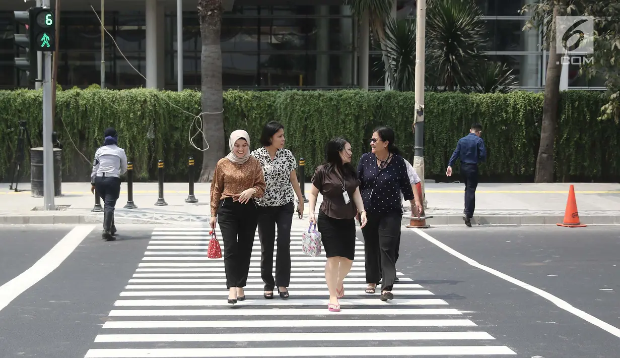 Pejalan kaki sedang menyebrang di pelican crossing di kawasan Thamrin, Jakarta, Minggu (29/7). Pelican crossing di kawasan Thamrin sudah bisa di gunakan pengganti JPO yang akan dibongkar. (Liputan6.com/Herman Zakharia)