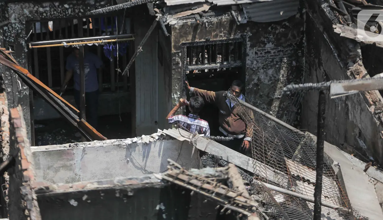 Warga berada di antara puing sejumlah rumah yang terbakar di Jalan Setia, RT 12/02, Bidara Cina, Jatinegara, Jakarta, Selasa (22/10/2019). Kebakaran pada Senin (21/10) sore itu diduga berasal dari hubungan arus pendek listrik hingga menyebabkan hangusnya 51 rumah. (Liputan6.com/Faizal Fanani)