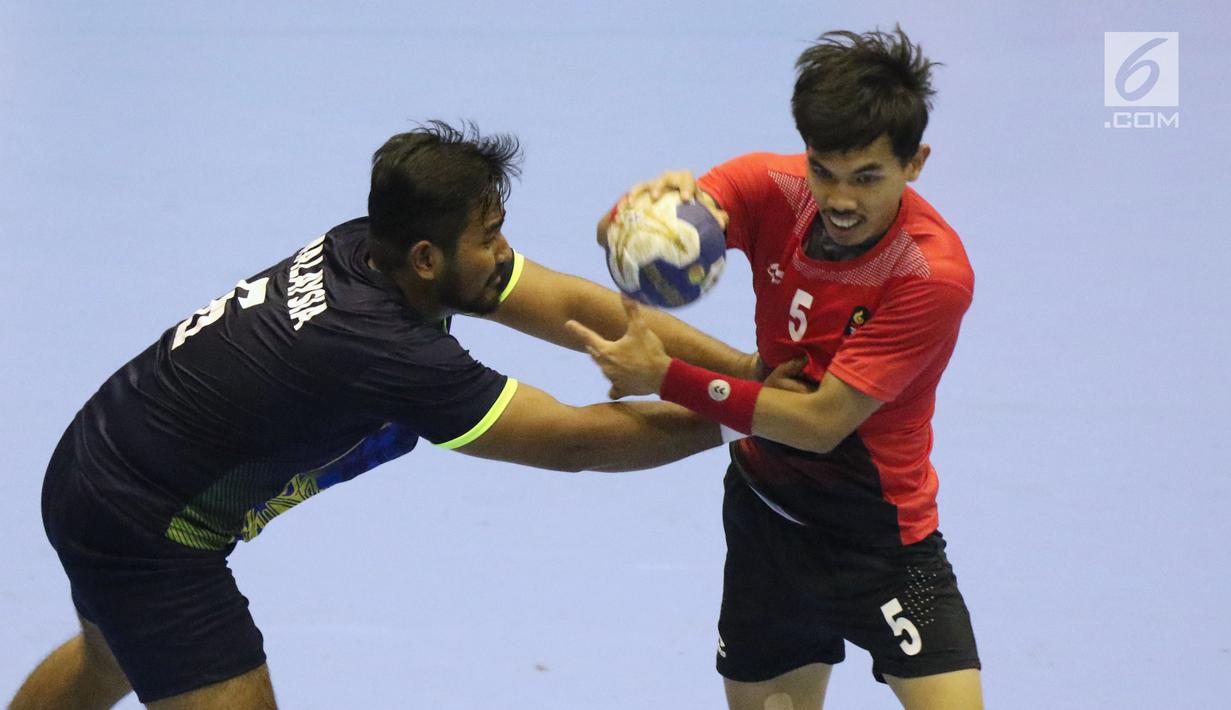 Pemain bola tangan Indonesia, Fitra Agung Aditya P (kanan) mencoba lolos dari kawalan pemain Malaysia pada penyisihan grup 3 bola tangan Asian Games 2018 di GOR PP POPKI, Jakarta, Minggu (26/8). Indonesia unggul 31-22. (Liputan6.com/Helmi Fithriansyah)