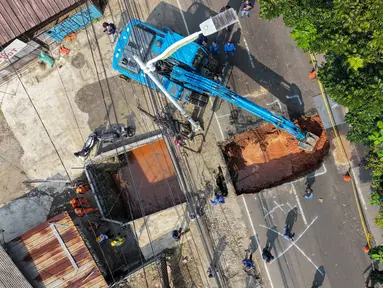 Foto udara menunjukkan aktivitas para pekerja menggunakan alat berat untuk membersihkan puing-puing dari lubang runtuhan yang terbentuk di Jalan Raya Lenteng Agung (arah Depok), Jakarta pada Jumat 29 Mei 2026. (BAY ISMOYO/AFP)