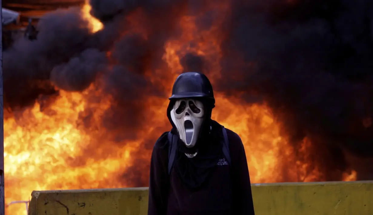 Demonstran anti-pemerintah di Venezuela mengenakan topeng hantu saat menggelar aksi di Caracas, Venezuela, Sabtu (26/5). Memasuki hari ke-56, aksi demonstrasi anti-pemerintah tersebut telah memakan korban jiwa 47 orang. (AP Photo)  