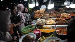 Sentra kuliner ini menyajikan berbagai makanan khas Sumatra Barat mulai dari makanan ringan hingga berat. Tampak dalam foto, orang-orang membeli makanan untuk berbuka puasa pada hari kedua bulan suci Ramadan 1447 Hijriah, di sebuah warung makan, Jakarta, Jumat 20 Februari 2026. (AP Photo/Dita Alangkara)