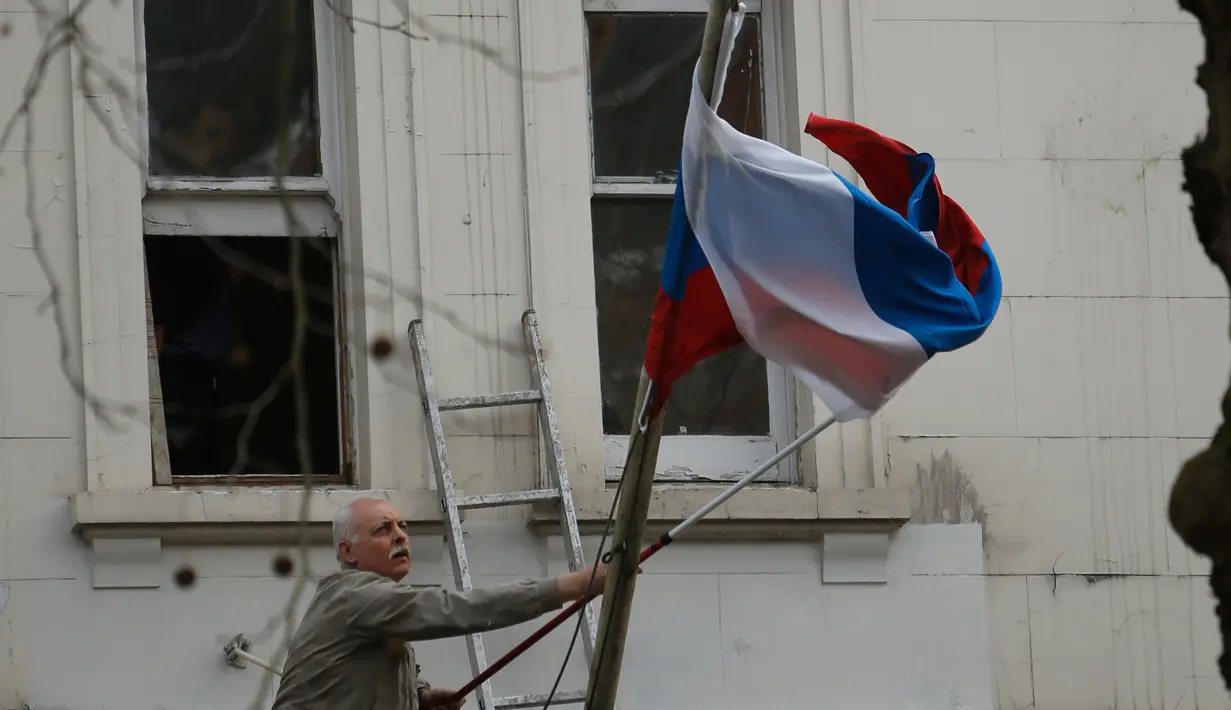 Seorang pria mengambil bendera nasional Rusia dari tiang di luar Kedutaan Besar Rusia di London, Rabu (14/3). Inggris diketahui mengusir 23 diplomat Rusia menyikapi kasus mantan agen ganda Rusia yang diduga diracun zat saraf langka. (AP/Alastair Grant)