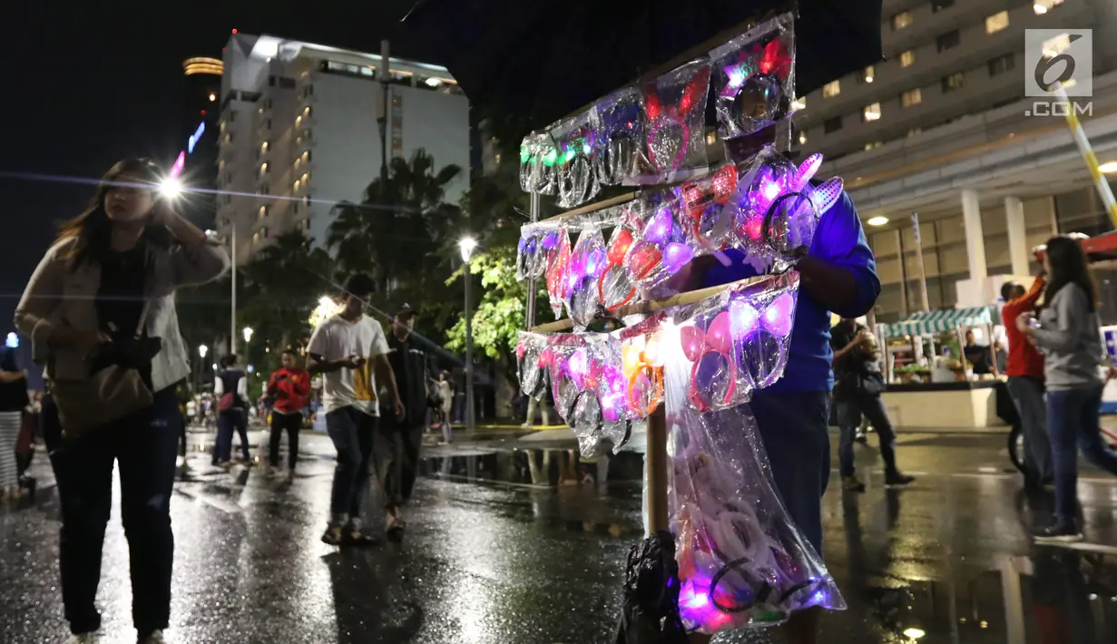 Pedagang menjual aksesoris rambut pada malam pergantian tahun di kawasan Bundaran HI, Jakarta, Senin (31/12). Pergantian tahun dimanfaatkan pedagang untuk mencari keuntungan dengan berjualan pernak pernik tahun baru.(Liputan6.com/Angga Yuniar)