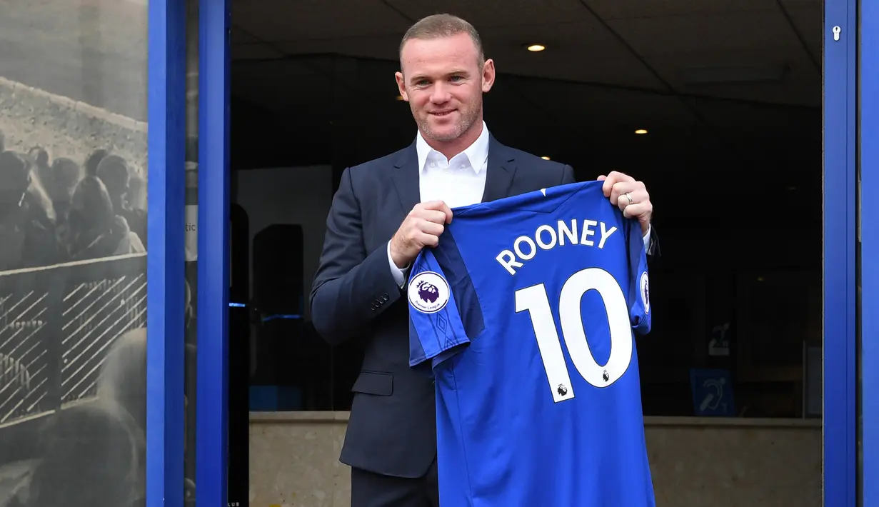 Penyerang baru Everton Wayne Rooney, memegang kostum tim barunya setelah konferensi pers di Goodison Park di Liverpool (10/8). Wayne Rooney dibeli Everton dari Manchester United. (AFP Photo/Paul Ellis)