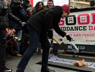 Seorang wanita melemparkan barang miliknya untuk dihancurkan dalam acara "Good Riddance Day" di Times Square, New York, Rabu (28/12). Good Riddance Day menjadi tradisi warga New York menghapus kenangan buruk selama satu tahun. (REUTERS/Darren Ornitz)