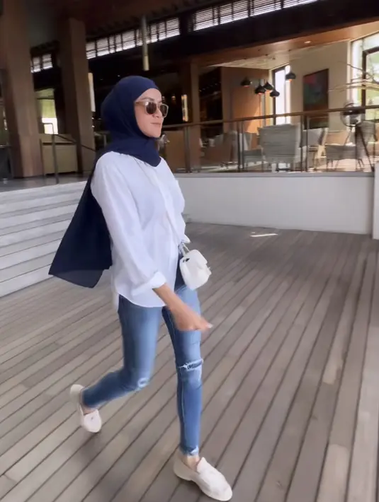 Masih dengan atasan kemeja putih lengan panjang, Olla memadukannya dengan kerudung navy dan celana denim panjangnya.  [Instagram/@ollaramlan]