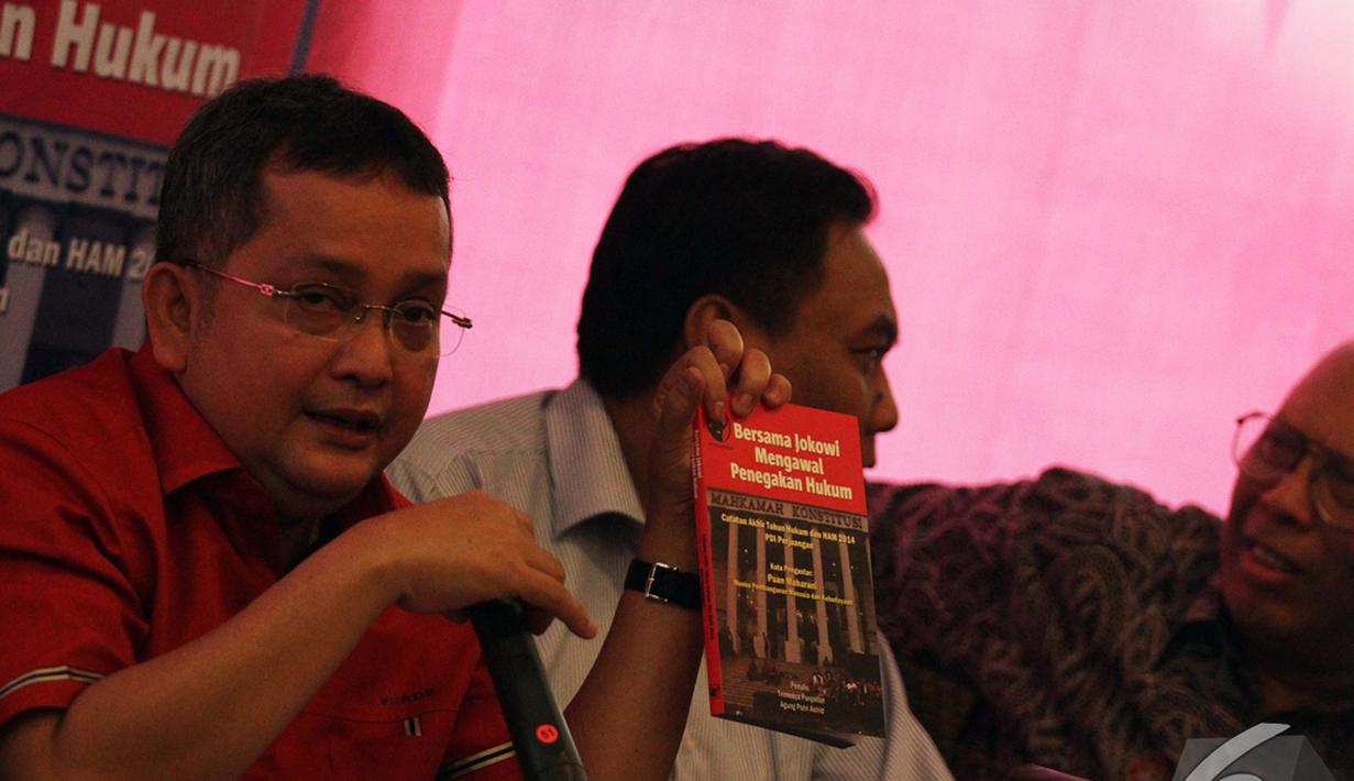 Ketua DPP bidang hukum PDIP Trimedya Panjaitan (kiri) menunjukkan buku 'Bersama Jokowi Mengawal Penegakan Hukum', Jakarta, Selasa (30/12/2014). (Liputan6.com/Faizal Fanani)