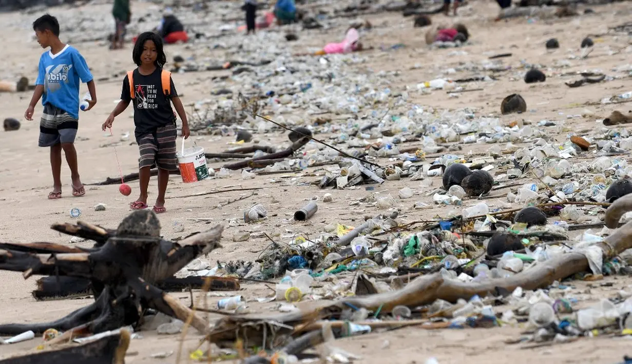 <p>Anak-anak berjalan melewati plastik dan sampah lainnya yang terdampar di Pantai Kedonganan, Kabupaten Badung, Bali, Indonesia, Rabu (12/4/2023). (SONNY TUMBELAKA/AFP)</p>