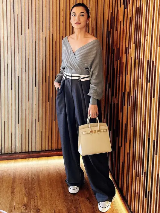 Ia juga tampil stylish dengan atasan knit abu-abu yang memerlihatkan keindahan pundaknya dipadukan celana navy. Dan menengteng tas Hermes putih gadingnya. credit: Instagram/(@chelseaoliviaa)