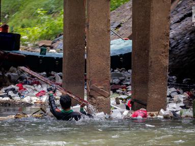 Aksi petugas PPSU bersihkan sampah yang tersangkut ditengah deras arus aliran anak kali Ciliwung, Jakarta, Senin (22/7/2019). Pembersihan sungai dari berbagai sampah tersebut dimaksudkan agar tidak ada penumpukan sampah dan sedimentasi saluran di sepanjang sungai. (Liputan6.com/Faizal Fanani)