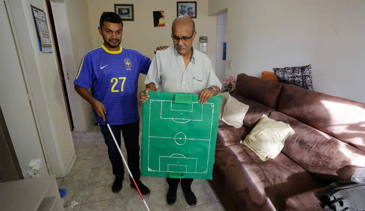 Carlos Junior bersama dengan ayahnya membawa miniatur lapangan sepak bola untuk merasakan berlangsungnya pertandingan babak 16 besar Piala Dunia 2018 antara Brasil melawan Meksiko di Sao Paulo, Brasil, (2/7). (AP Photo / Nelson Antoine)