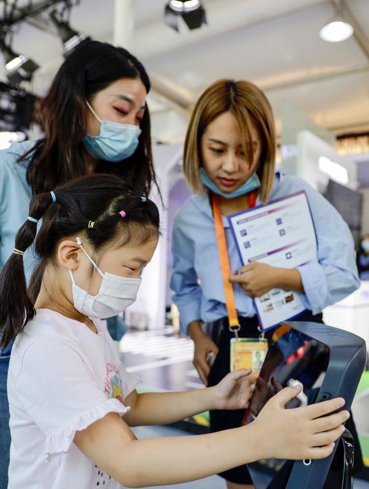 Seorang gadis kecil menjajal robot layanan rumah pintar di area ekshibisi layanan komunikasi 5G dalam Pameran Perdagangan Jasa Internasional China (CIFTIS) 2020 di Beijing, ibu kota China, pada 5 September 2020. CIFTIS digelar pada 4-9 September di Beijing. (Xinhua/Li Muzi)
