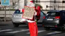Remi Le Calvez mengenakan kostum Santa Claus, menunggu mobil yang bisa ditumpangi di Paris, Prancis, Selasa (6/12). Pada perjalannya kali ini, Remi mencari tumpangan yang akan membawanya ke Rovaniemi di Lapland, Finlandia Utara. (Reuters/Benoit Tessier)