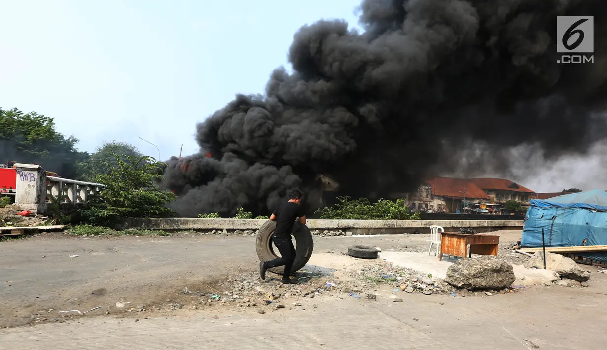 Warga memindahkan sebuah ban saat kebakaran melanda sebuah gudang di Jalan Kampung Bandan, Ancol, Jakarta Utara, Kamis (5/7). (Kapanlagi.com/Budy Santoso)