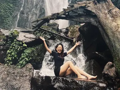 Natalie Zenn terlihat ceria saat berada di bawah air terjun dengan aliran air yang terbilang deras. Tak takut hanyut, wanita 22 tahun ini sukses mencuri perhatian lewat penampilannya dengan outfit santai. (Liputan6.com/IG/@nataliezenn24)