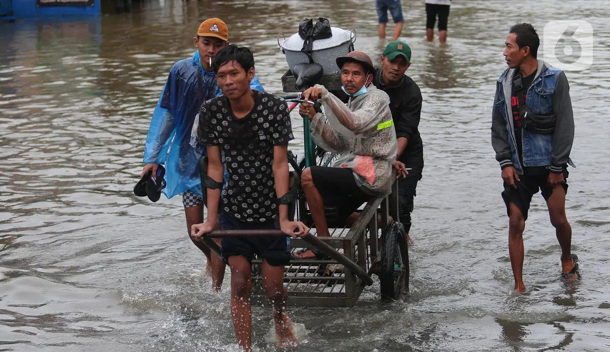Warga memanfaatkan jasa gerobak untuk melintasi banjir di Jalan KH Hasyim Ashari, Kota Tangerang, Banten, Sabtu (16/7/2022). Warga sekitar membantu para pengendara yang melintas agar tidak terkena banjir dengan menawarkan jasa gerobak. (Liputan6.com/Angga Yuniar)