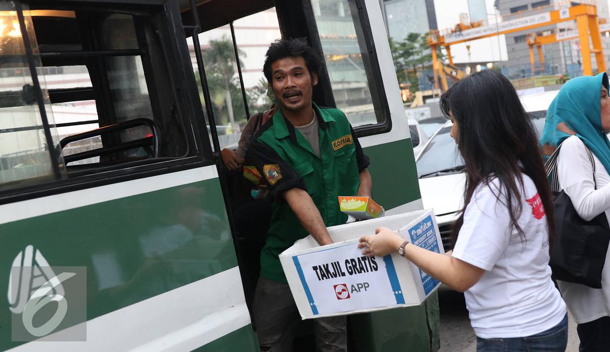 Kondektur mengambil takjil gratis yang dibagikan oleh Karyawan Asia Pulp & Paper (APP) Sinar Mas di kawasan Bundaran HI, Jakarta (24/6). (Liputan6.com/ Immanuel Antonius)