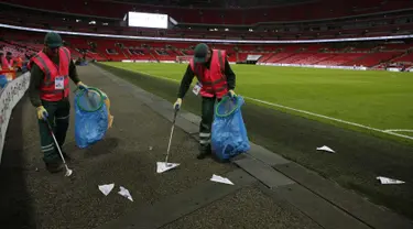 Petugas mengumpulkan pesawat terbang kertas yang dilemparkan suporter selama pertandingan Inggris melawan Slovenia di kualifikasi Piala Dunia 2018 di stadion Wembley, London, (5/10). AFP Photo/Adrian Dennis)