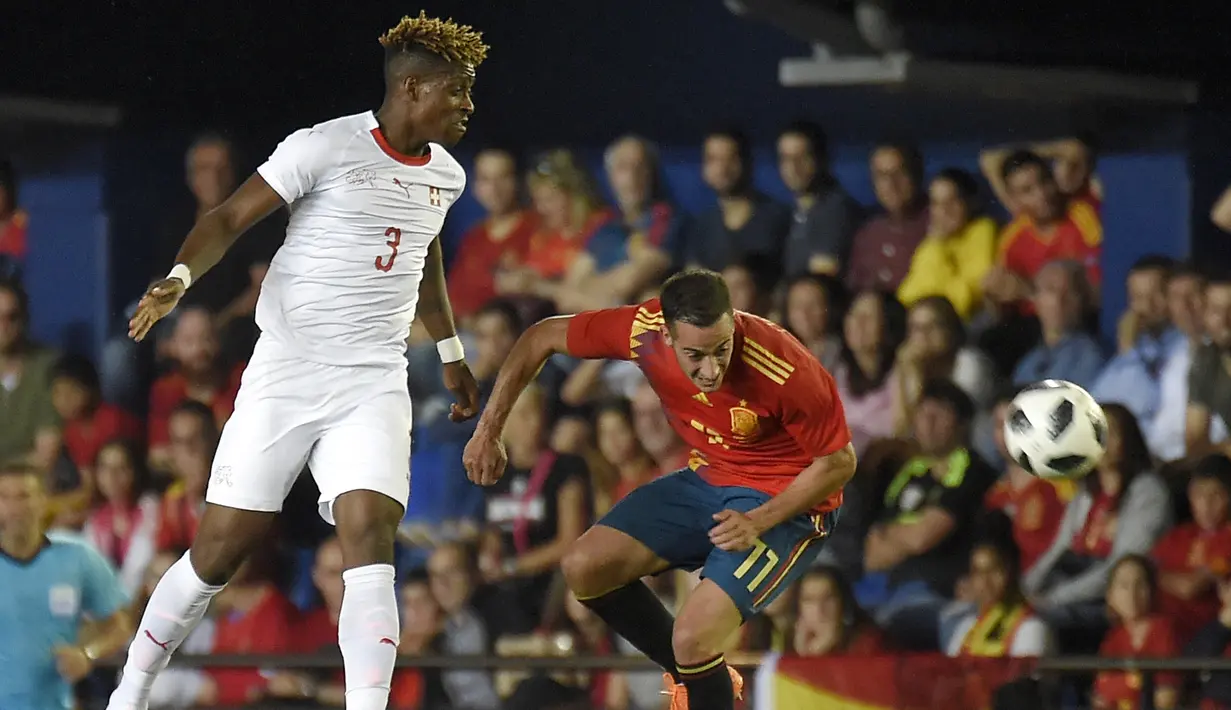 Bek Swiss, Francois Moubandje, duel udara dengan striker Spanyol, Lucas Vazquez, pada laga persahabatan di Stadion La Ceramica, Vila-real, Minggu (3/6/2018). Kedua negara bermain imbang 1-1. (AFP/Jose Jordan)